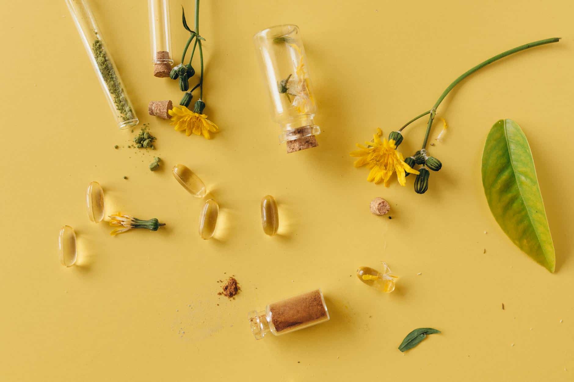 herbal capsules and powder on yellow surface